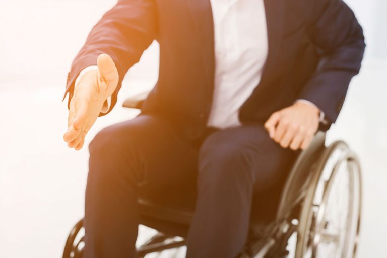Trabajador vestido de traje esperando para estrechar la mano. Imagen impersonal de un trabajador ofreciendo su mano, sentado en silla de ruedas.