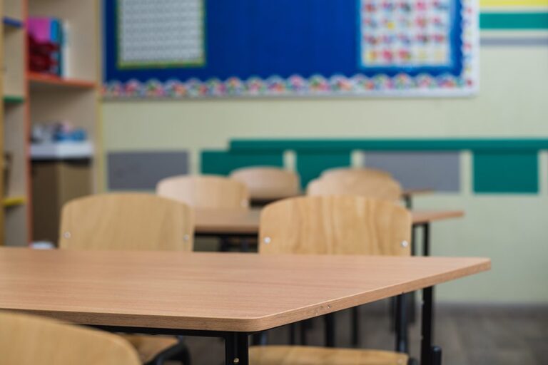 Aula sin alumnos Foto genérica de un aula con mesas y sillas de madera sin alumnos.