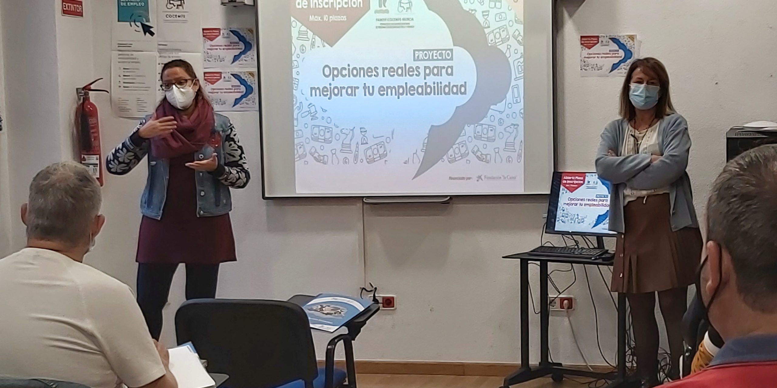 Presentación curso – Opciones reales para mejorar la empleabilidad Mª José Fernández y Encarna Navarro están junto a la pantalla con el cartel de "Opciones reales para mejorar tu empleabilidad".