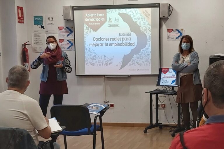 Presentación curso – Opciones reales para mejorar la empleabilidad Mª José Fernández y Encarna Navarro están junto a la pantalla con el cartel de "Opciones reales para mejorar tu empleabilidad".