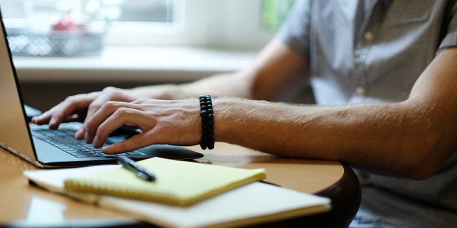 Hombre delante de un ordenador tecleando.