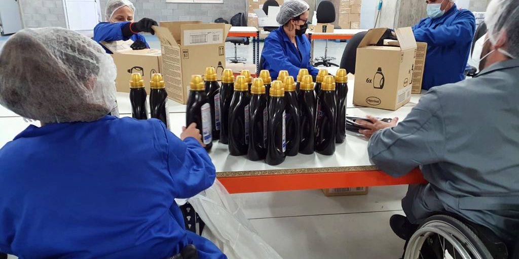 Trabajadores de SERVIGEST manipulando botes sobre una mesa grande.