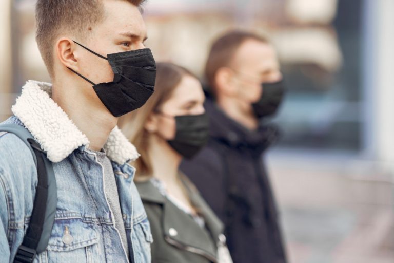 jovenes medidas anticovid Tres jóvenes con mascarillas negras mirando hacia el lado derecho.